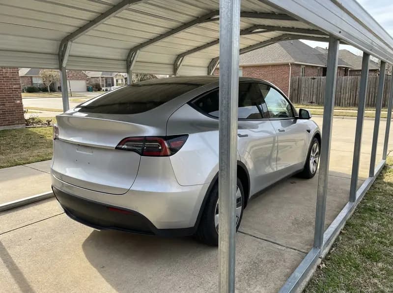 SUV parked under an attached steel carport roof with clear space on all sides on a US driveway